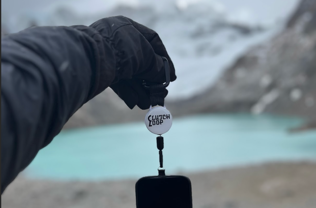 Hiker with phone tethered to backpack using ClutchLoop on a mountain trail