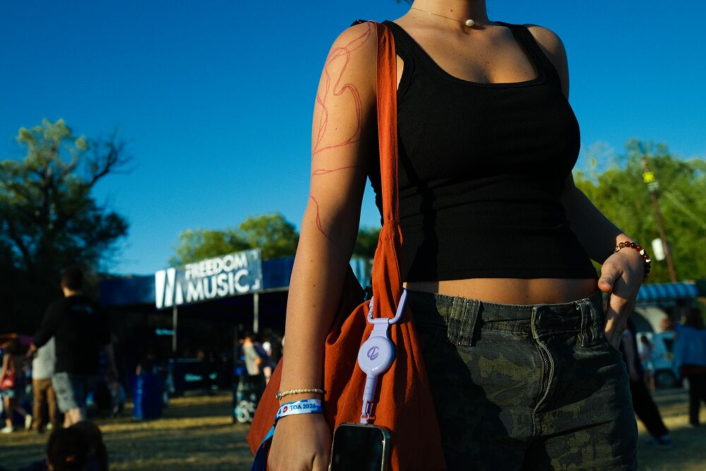 Traveler with a red bag and a phone tethered at her side under a blue sky