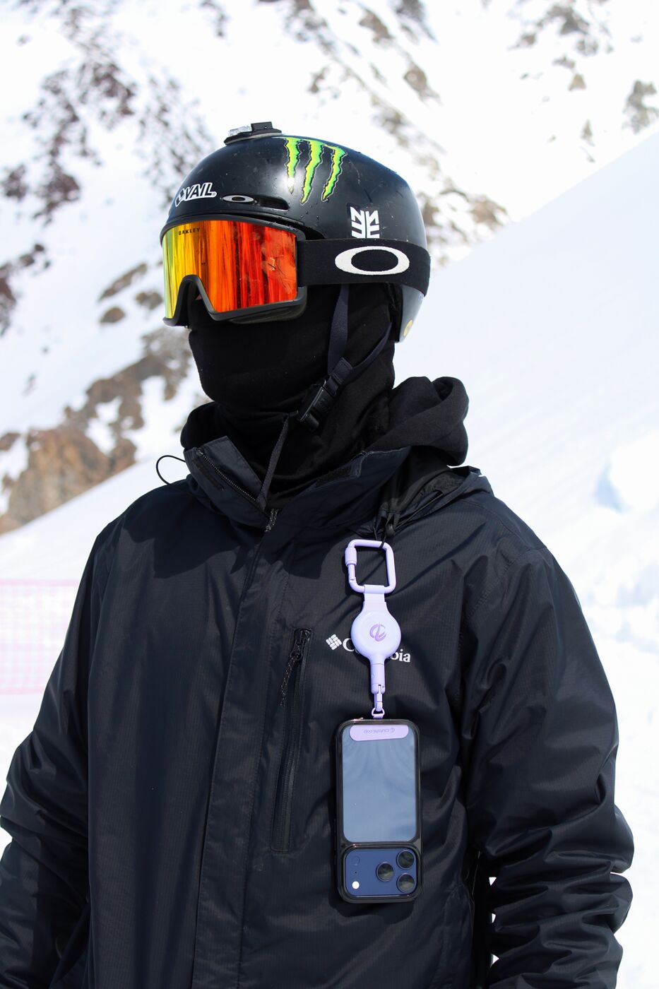 Snowboarder in goggles with a phone tethered to their jacket by ClutchLoop