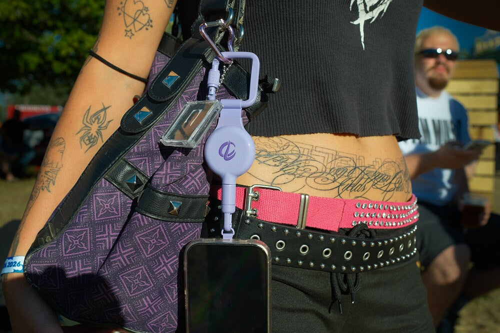 Lavender ClutchLoop on a patterned shoulder bag with studded belts at a festival