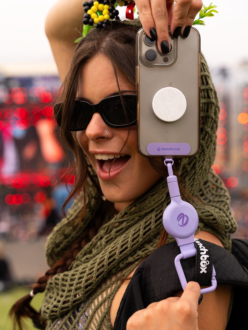 Woman in sunglasses holding up her phone with a lavender ClutchLoop